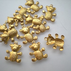 Könnte beinhalten: Eine Sammlung kleiner, goldfarbener Teddybär-Anhänger. Jeder Anhänger hat eine strukturierte Oberfläche mit sichtbaren Details wie dem Gesicht, den Armen und Beinen des Bären. Die Anhänger haben oben eine Schlaufe zum Befestigen an Schmuck oder anderen Bastelarbeiten.