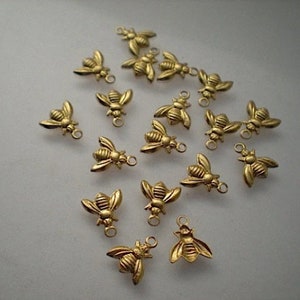May include: A collection of 18 gold-toned bee charms with a loop for attaching to jewellery or crafts.