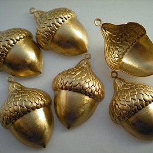 Op de afbeelding: Zes gouden eikelbedels met een getextureerd oppervlak. De bedels zijn perfect voor het maken van sieraden of knutselen.