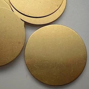 Op de afbeelding: Een set van vijf ronde, goudkleurige metalen schijven. De schijven zijn glad en hebben een licht getextureerd oppervlak.
