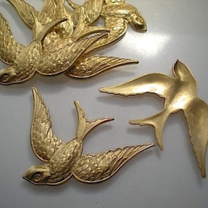 Könnte beinhalten: Fünf goldfarbene Metallschwalben-Ornamente. Die Vögel sind im Flug mit ausgebreiteten Flügeln. Die Vögel sind mit strukturierten Federn verziert.