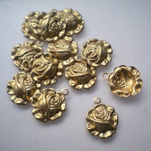 May include: A collection of gold-colored rose charms. Each charm is a detailed miniature rose with a loop for attaching to jewelry or other crafts. The charms are scattered across a light background, showcasing their intricate design.