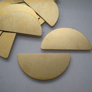 May include: A set of gold-colored metal half-circle shapes. The shapes are arranged in a semi-circle pattern on a white surface.