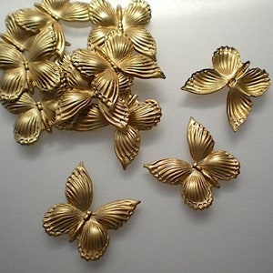 May include: A collection of gold-colored butterfly embellishments. The butterflies have detailed wing patterns and are arranged in a scattered composition. The metallic finish gives them a decorative appearance.