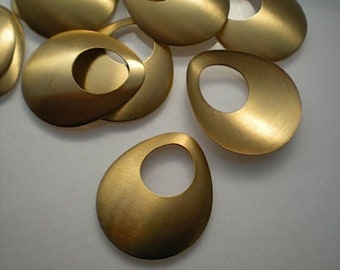 May include: A collection of teardrop-shaped, brushed brass pendants with a large oval cutout. The pendants have a smooth, matte finish and are arranged on a light-colored surface. The design is simple and modern.