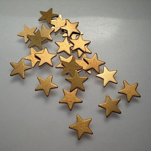 May include: A scattering of gold-colored metal star-shaped embellishments.