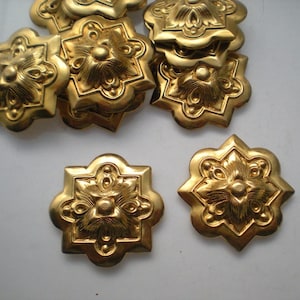 以下が含まれることがあります： 星形のデザインの金色の金属製の装飾品が10個あります。各装飾品は、花柄の隆起した中心を持っています。