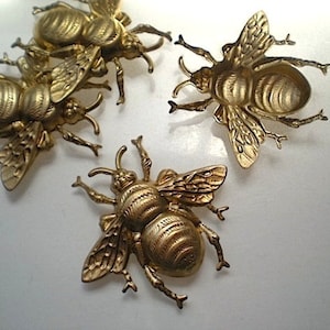May include: Four gold-colored metal bee figurines. The bees have detailed wings and bodies.