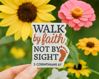 Puede incluir: Una pegatina blanca con el texto "WALK by faith NOT BY SIGHT" en azul marino y óxido, con un gráfico de huella. La pegatina se sostiene frente a un fondo de flores amarillas y rosas.
