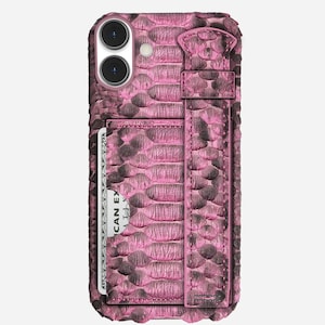Könnte beinhalten: Rosa und schwarze Handyhülle mit Schlangenlederstruktur und Kartenhalter. Die Hülle hat einen Riemen und einen Schlitz für eine Kreditkarte. Die Handyhülle hat zwei Kameralinsen und einen Blitz.