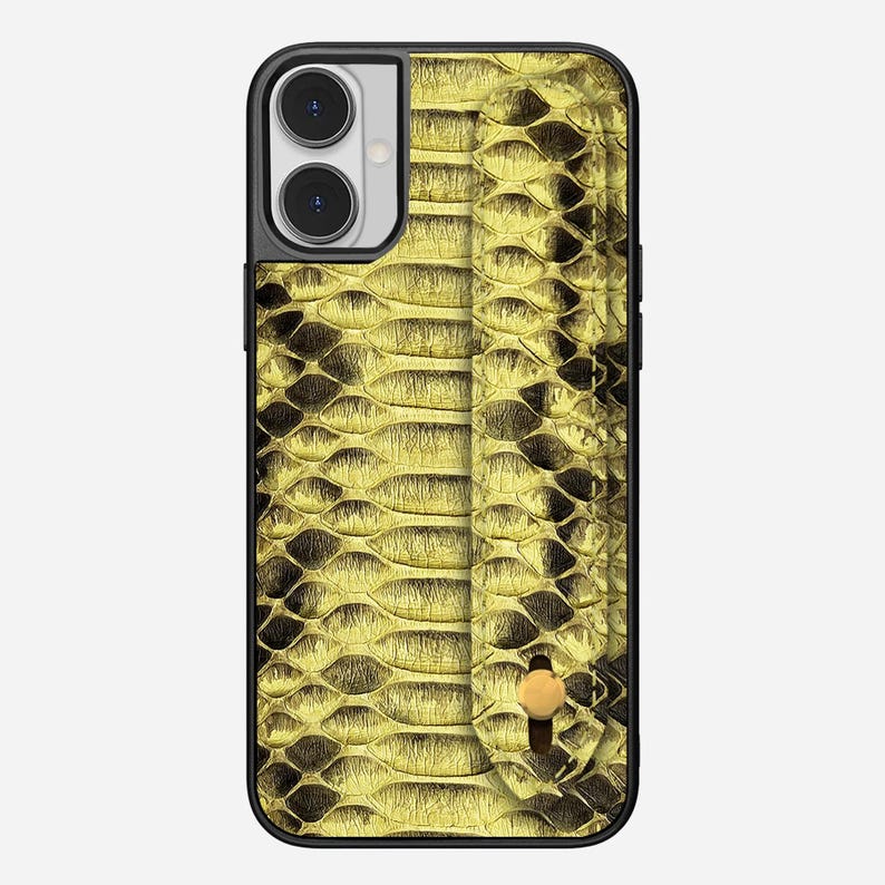 Peut inclure: Coque de t&eacute;l&eacute;phone noire avec un motif peau de serpent dor&eacute;. L'&eacute;tui est dot&eacute; d'une poign&eacute;e int&eacute;gr&eacute;e et d'une d&eacute;coupe pour appareil photo &agrave; double objectif. Le motif peau de serpent pr&eacute;sente un aspect textur&eacute; en forme d'&eacute;cailles.