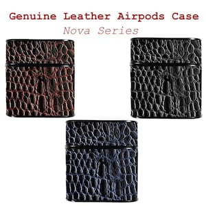 May include: Genuine leather Airpods cases in three colors: brown, black, and blue. The cases have a textured, crocodile-like pattern and a black trim. The text "Genuine Leather Airpods Case Nova Series" is at the top.