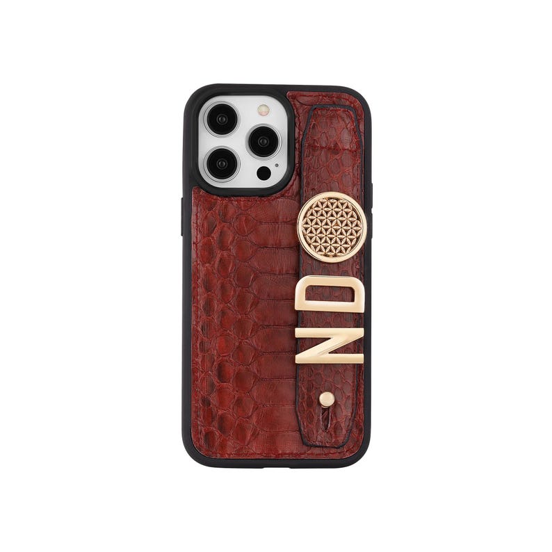 May include: A brown textured phone case with a black border. The case features a gold-colored circular design and the letters "ND" in gold. The case is designed to fit a smartphone.