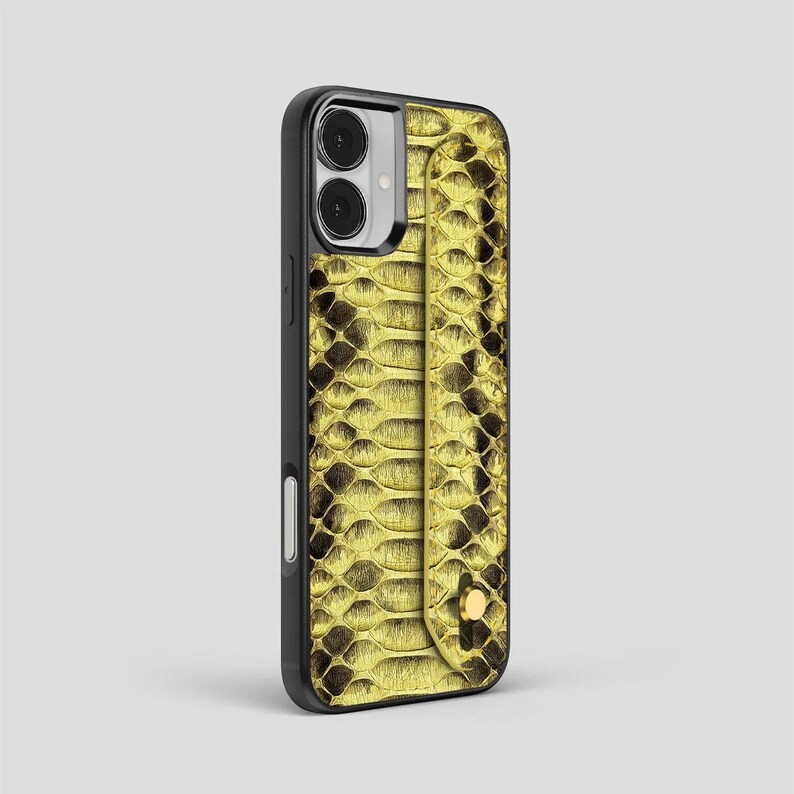 Peut inclure: Un &eacute;tui de smartphone noir avec un motif de peau de serpent jaune. L'&eacute;tui est dot&eacute; d'une dragonne et d'une fermeture &agrave; bouton dor&eacute;e. L'&eacute;tui est con&ccedil;u pour prot&eacute;ger le t&eacute;l&eacute;phone.