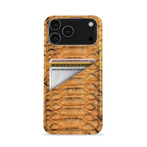 May include: A phone case featuring a snakeskin design in brown and tan hues. The case incorporates a cardholder, displaying three cards. The phone case has a black camera module with three lenses.