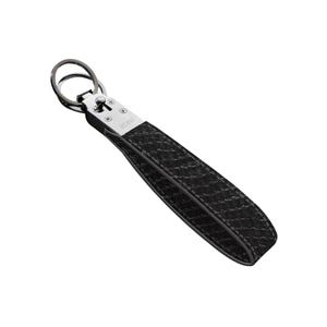 May include: Black leather keychain wrist strap with a woven pattern. The strap is attached to a silver metal clasp and a dark metal key ring. The word "VELANO" is printed on the clasp.