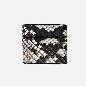May include: A square case featuring a black and white snakeskin pattern. The case has a black rim and a small, black button. The snakeskin design is a mix of black, white, and grey scales.