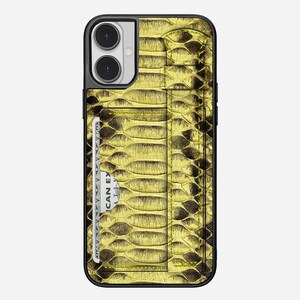 May include: A gold and black iPhone case with a snakeskin pattern. The case has a built-in card holder with a credit card partially visible. The case is designed to fit an iPhone and has a black border.