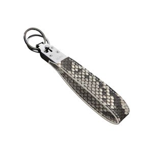 May include: A keychain with a snakeskin pattern wrist strap. The strap is black, white, and gray. The metal hardware is silver and has a ring for keys. The word "VELANO" is printed on the strap.