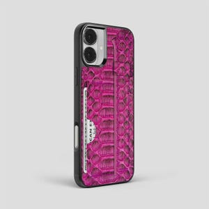 Könnte beinhalten: Eine magentafarbene Handyhülle mit einem strukturierten Schlangenhautmuster. Die Hülle hat einen schwarzen Rand und einen Schlitz für eine Kreditkarte. Auf der Kreditkarte steht der Text "AMERICAN EXPRESS".