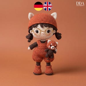 Peut inclure: Poupée au crochet faite à la main sur le thème du panda roux. La poupée porte une tenue couleur rouille, un chapeau assorti avec des oreilles blanches et des lunettes rondes. Elle tient une petite peluche panda roux. La poupée a les cheveux foncés.