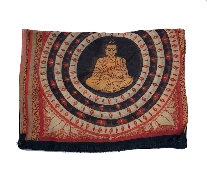 May include: A black, red, and white fabric square with a circular design featuring a golden Buddha figure in the center. The Buddha is sitting in a meditative pose with his hands in his lap. The design is surrounded by concentric circles of red, white, and black.