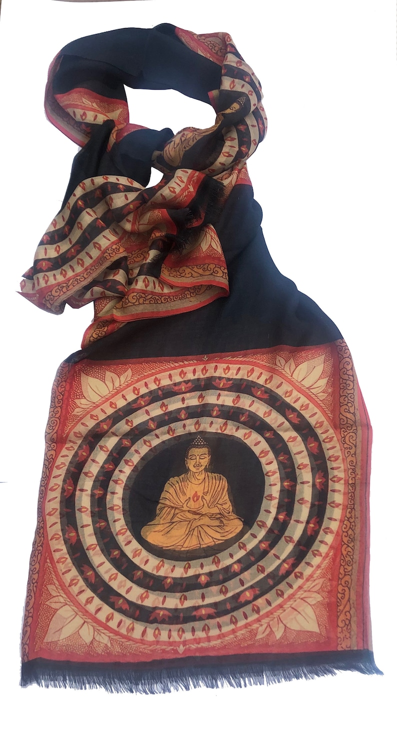 May include: A black and red patterned scarf with a circular design featuring a seated Buddha in the center. The Buddha is depicted in a yellow robe with a halo and is surrounded by concentric circles of red, white, and black.
