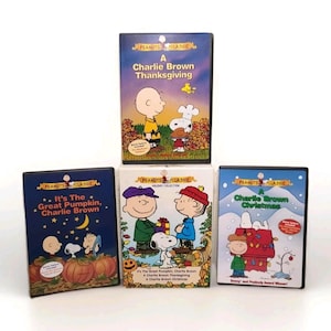 May include: Four Peanuts Classic DVD cases featuring Charlie Brown and Snoopy. Titles include "A Charlie Brown Thanksgiving", "It's The Great Pumpkin, Charlie Brown", and "A Charlie Brown Christmas". The cases have colorful illustrations.