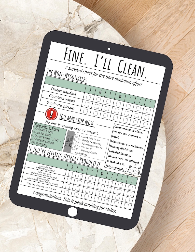 May include: A digital tablet displays a printable cleaning checklist titled "FINE. I'LL CLEAN." The sheet includes sections for daily tasks, a "You May Stop Now" section, and a "If You're Feeling Weirdly Productive" section. The tablet rests on a light-colored surface.