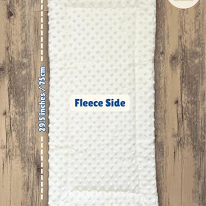 May include: A white fleece baby blanket, 29.5 inches long and 13.8 inches wide, with a textured surface. The blanket has a thickness of 0.8 inches. The text "Fleece Side" is visible. Handmade item.