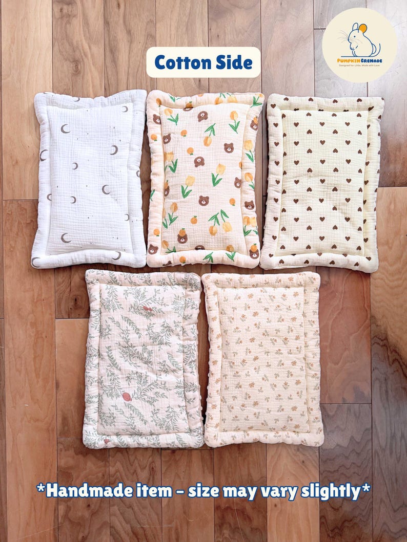 Puede incluir: Cinco cojines rectangulares de algod&oacute;n con esquinas redondeadas y bordes acolchados. Los patrones incluyen blanco con lunas oscuras, crema con osos marrones y tulipanes amarillos, crema con corazones marrones, follaje verde y peque&ntilde;os estampados florales.