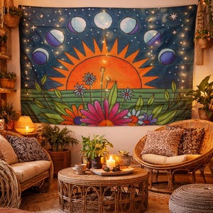 May include: A tapestry featuring a vibrant sun and moon phases design. The artwork includes a large orange sun, colorful flowers, and a dark blue background with stars and moon phases. The tapestry is displayed in a cozy, bohemian-style living space.