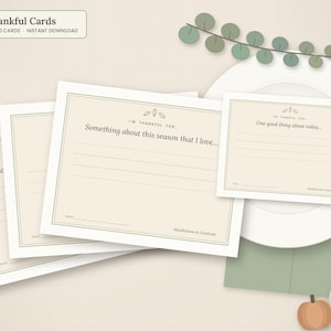 May include: A set of cream-colored Thankful Cards with dark brown text and thin borders. The cards feature prompts like 'Something about this season that I love' and 'One good thing about today' with lines for writing, plus the text 'Mindfulness & Gratitude'.