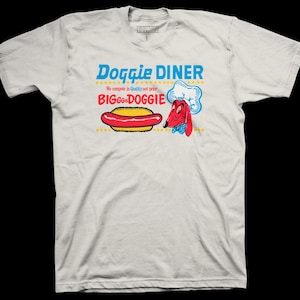 May include: White t-shirt featuring a retro-style graphic for "Doggie Diner." The design includes a hot dog, a chef dog character, and the text "BIG Good Doggie." The shirt has a crew neck and short sleeves.