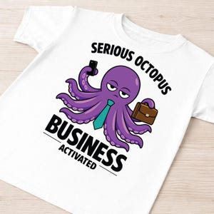 Puede incluir: Camiseta blanca con un diseño de pulpo de dibujos animados. El pulpo es morado, lleva una corbata turquesa y sostiene un teléfono y un maletín. El texto dice "SERIOUS OCTOPUS BUSINESS ACTIVATED."