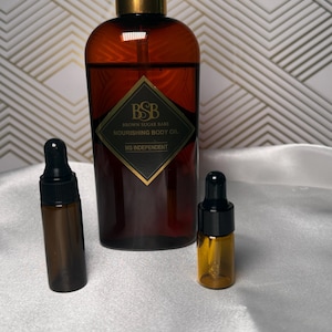 May include: A brown glass bottle of body oil with a black and gold pump, flanked by two smaller dropper bottles. The label reads "Brown Sugar Babe Nourishing Body Oil" and "MS Independent". The background is a white surface with a gold geometric pattern.