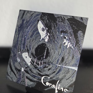 May include: A square print with a scene from the film "Coraline." The image shows a character confronting a threatening figure against a swirling, dark backdrop. The title "Coraline" is written in white script at the bottom.