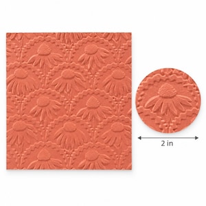 May include: A square terracotta-colored rubber stamp sheet featuring a repeating embossed pattern of stylized daisy-like flowers within scalloped circular frames, accompanied by a circular detail showing a 2-inch diameter measurement.