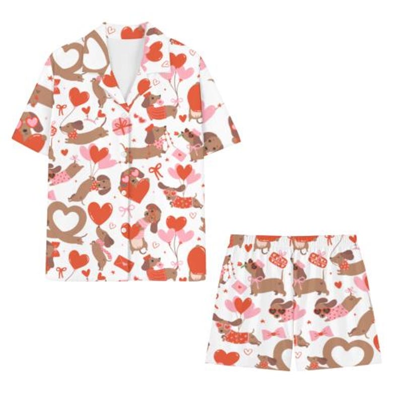 May include: White pyjama set patterned with brown dachshunds, red hearts, and pink balloons. The short-sleeved top and shorts feature a repeating design of the dogs holding balloons and gifts.
