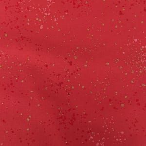 Peut inclure: Tissu rouge avec un motif tacheté. Le tissu a un fond rouge uni avec des mouchetures dorées et blanches éparpillées. Les mouchetures varient en taille et en densité, créant un aspect texturé.