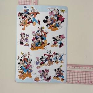 May include: A rectangular sticker sheet featuring various colorful illustrations of Disney characters including Mickey Mouse, Minnie Mouse, Donald Duck, Daisy Duck, Goofy, and Pluto. A clear plastic ruler is visible along the top and right edges.