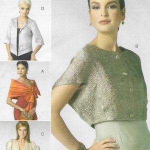 May include: Vogue Patterns V8721 sewing pattern envelope featuring four jacket and wrap designs. Includes a textured cropped jacket, a draped orange wrap, a light-colored bolero, and a silver-toned jacket. Text includes V8721, Vogue Patterns, and Elizabeth Gillett NYC.