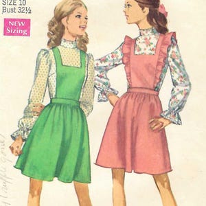 May include: A vintage Simplicity sewing pattern envelope 8026 for a jumper in size 10 with a 32.5 inch bust. The illustration shows two variations: a green jumper over a yellow polka dot blouse and a pink ruffled jumper over a floral blouse.