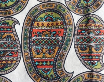 May include: Close-up of a fabric with a repeating paisley pattern. The paisley shapes are in shades of orange, green, teal, and gold, outlined in dark brown, against a white background. The design has intricate floral and geometric details.