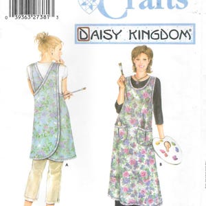 May include: Simplicity Crafts Daisy Kingdom sewing pattern 5201 for a sleeveless apron with a floral print. The pattern shows two views: view A is a shorter apron over pants, and view B is a longer apron over a dress, both featuring pockets.