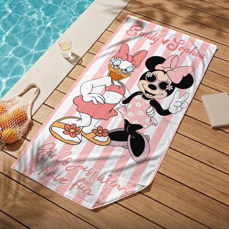 May include: A pink and white striped beach towel featuring Daisy Duck and Minnie Mouse. The towel has the text "Emily & Sophia" and "Girls just wanna have fun". The cartoon characters are wearing sunglasses and dresses.