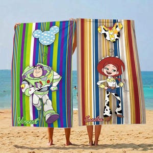 Puede incluir: Dos toallas de playa con dise&ntilde;os de personajes de dibujos animados. Una presenta a Buzz Lightyear con el nombre "Vincent" y un globo de Mickey Mouse. La otra toalla tiene a Jessie con el nombre "Sandra" y un globo de Mickey Mouse. Ambas toallas tienen rayas verticales.