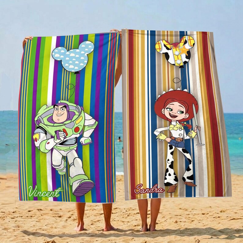 Puede incluir: Dos toallas de playa con dise&ntilde;os de personajes de dibujos animados. Una presenta a Buzz Lightyear con el nombre "Vincent" y un globo de Mickey Mouse. La otra toalla tiene a Jessie con el nombre "Sandra" y un globo de Mickey Mouse. Ambas toallas tienen rayas verticales.