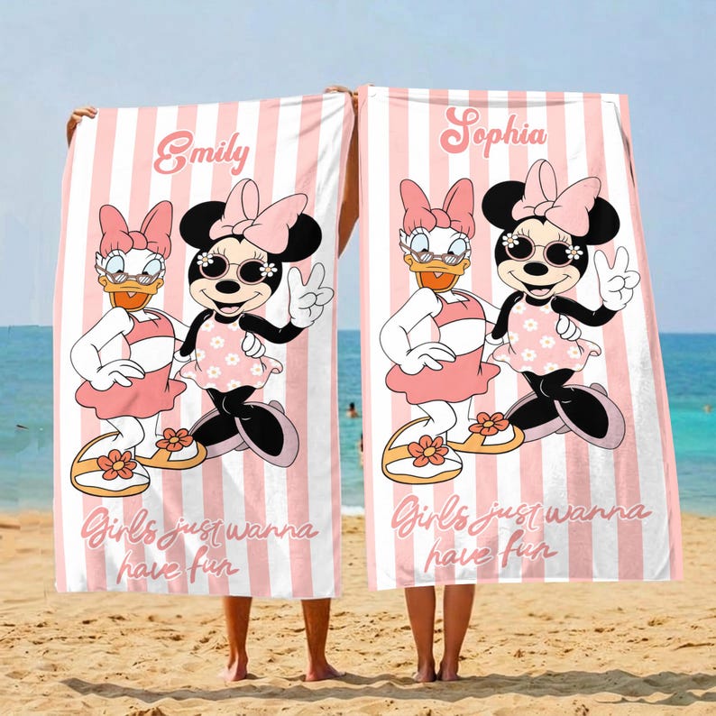 May include: Two beach towels with pink and white stripes, each featuring a cartoon of Minnie Mouse and Daisy Duck. The towels have the names "Emily" and "Sophia" printed on them, along with the phrase "Girls just wanna have fun."