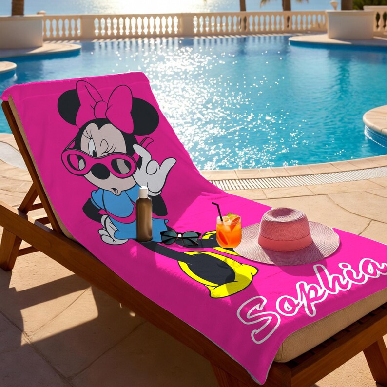 K&ouml;nnte beinhalten: Ein leuchtend pinkfarbenes Strandtuch mit Minnie Mouse, die eine Sonnenbrille und ein blaues Kleid tr&auml;gt. Das Handtuch liegt auf einer Holzliege am Pool. Ein rosa Sonnenhut, eine Sonnenbrille und ein Getr&auml;nk befinden sich ebenfalls auf dem Handtuch. Der Name "Sophia" steht auf dem Handtuch.
